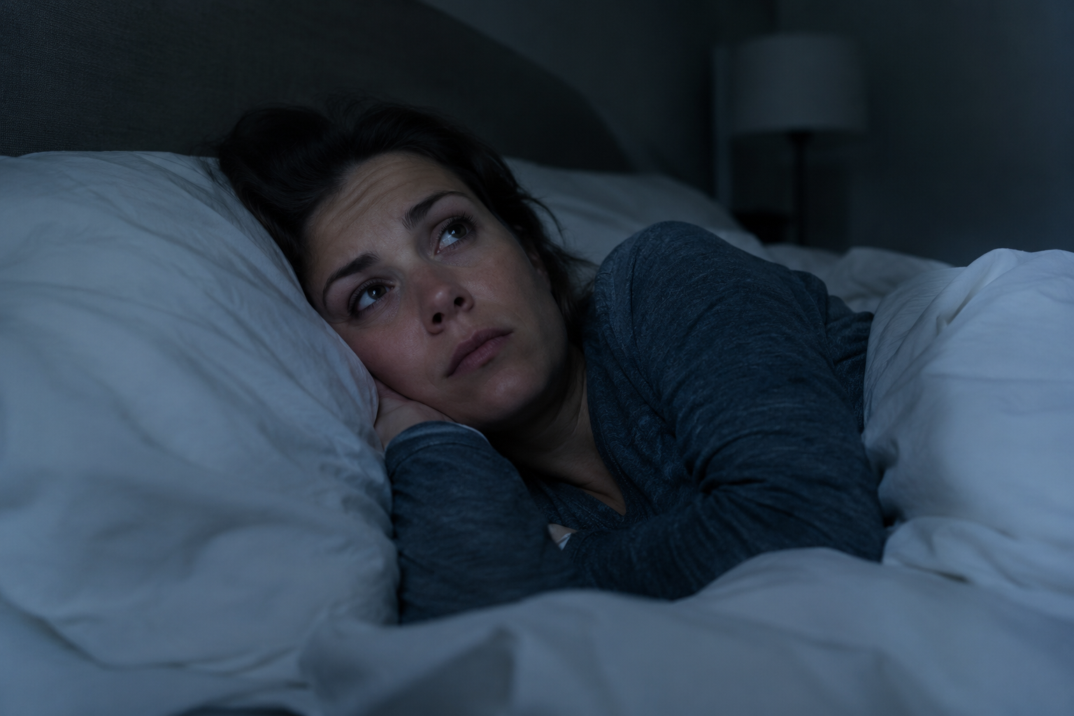 Woman awake in bed at night wondering why do I wake up at 3am